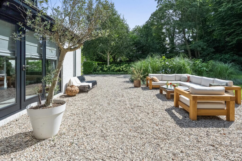 Outdoor seating area with white cushions and greenery.