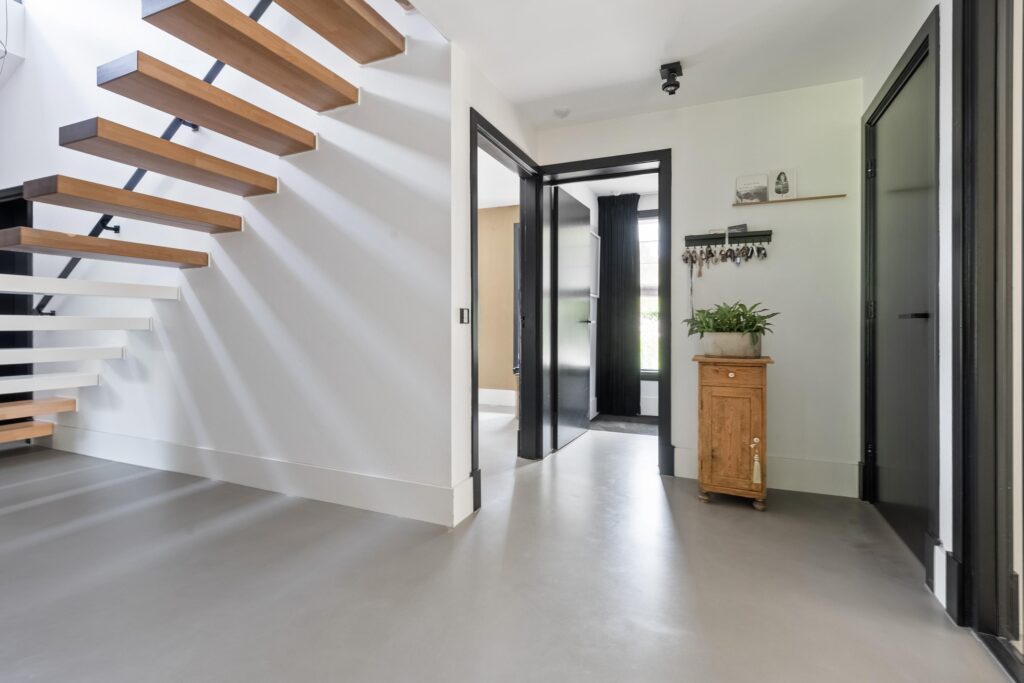 Modern hallway with wooden staircase and plant decor.