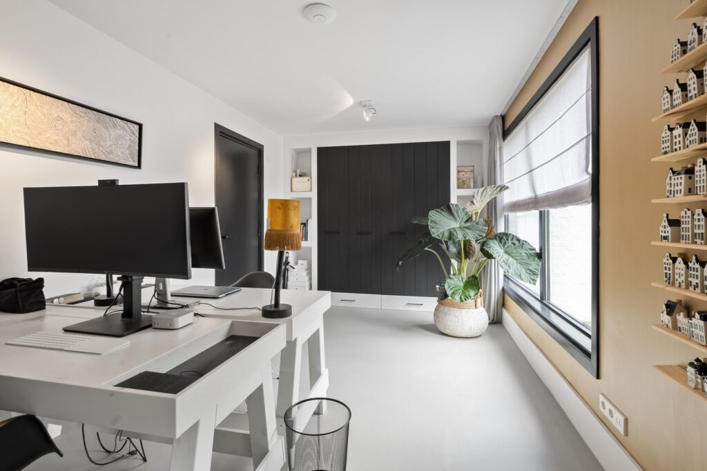 Modern office with desk, plant, and window shade.