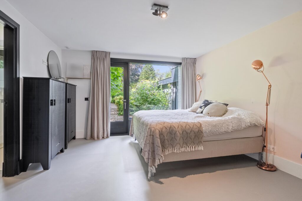 Modern bedroom with bed, cabinets, and garden view.