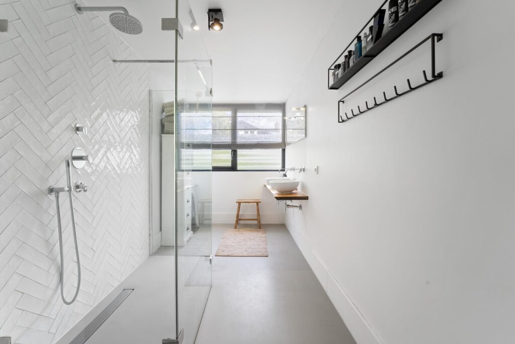 Modern white bathroom with glass shower and sink.