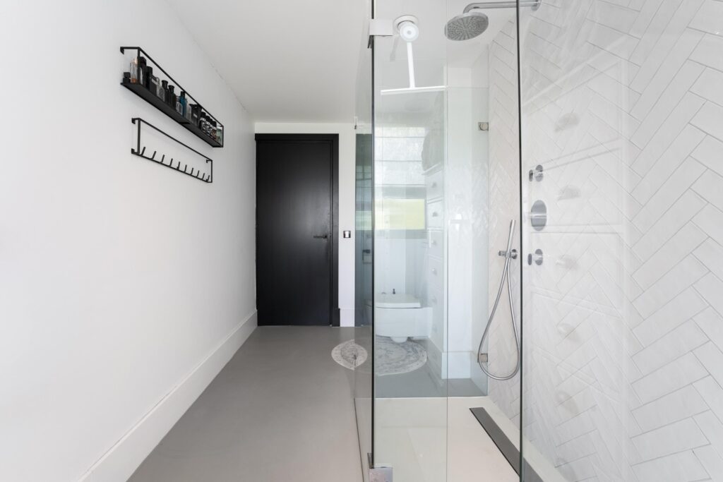 Modern bathroom with glass shower and black door.
