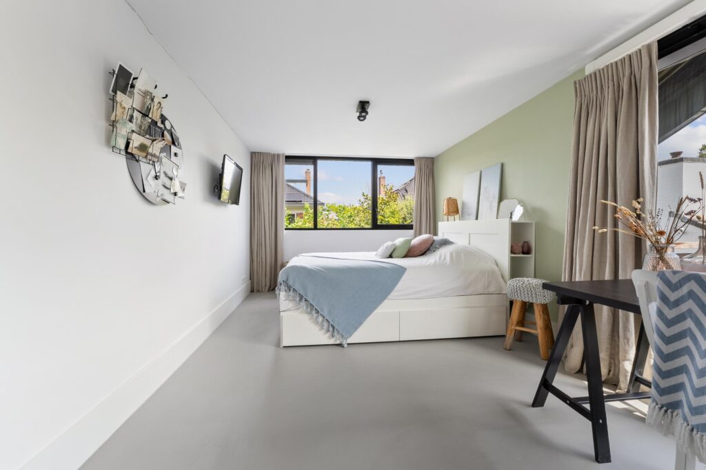 Modern bedroom with large window and neutral decor.