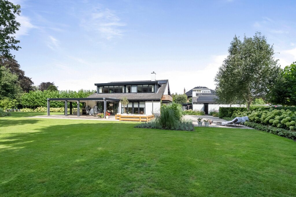 Modern house with large green yard, sunny day.