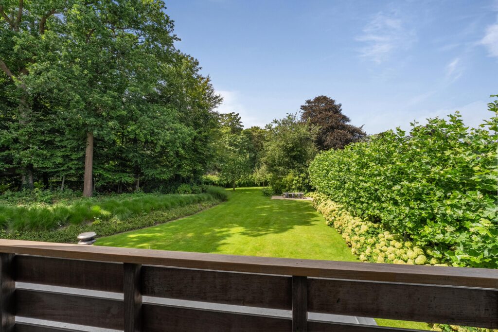 Lush garden view from a wooden balcony.