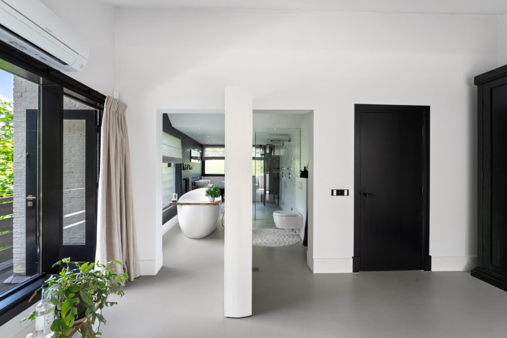 Modern bathroom with freestanding tub and large windows.