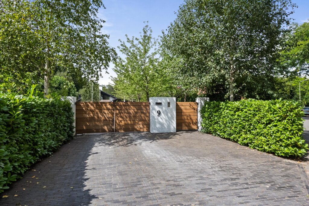 Wooden gate with brick driveway and hedges