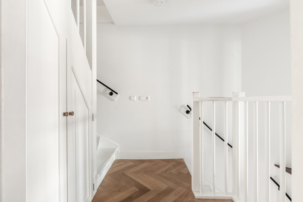 Modern indoor staircase with wooden steps and white rails.