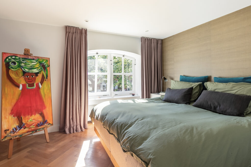 Bedroom with art painting and large window.