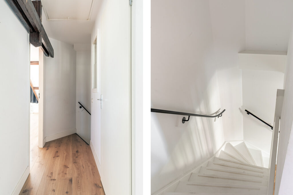 Narrow hallway and stairwell with wooden and white details.
