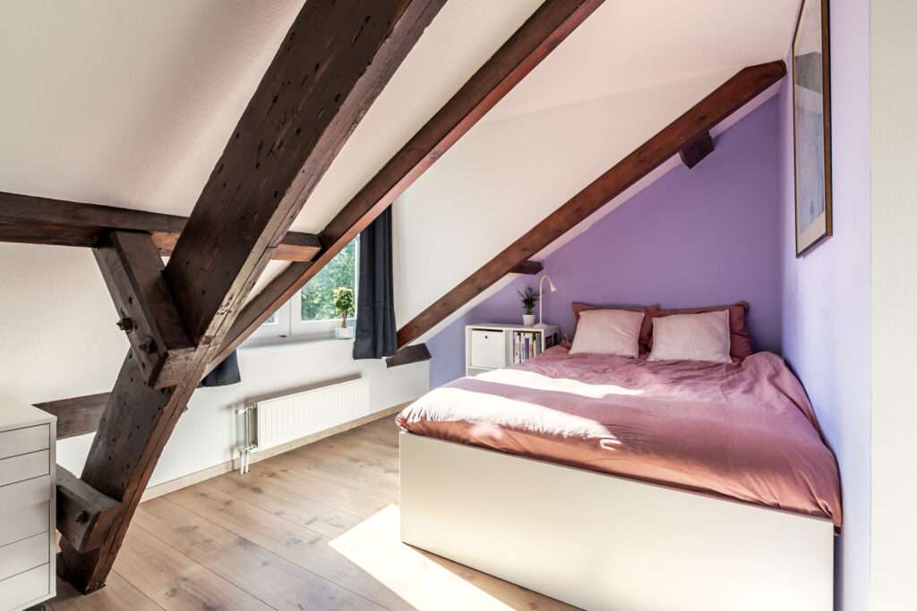 Cozy attic bedroom with sloped ceiling and sunlight.