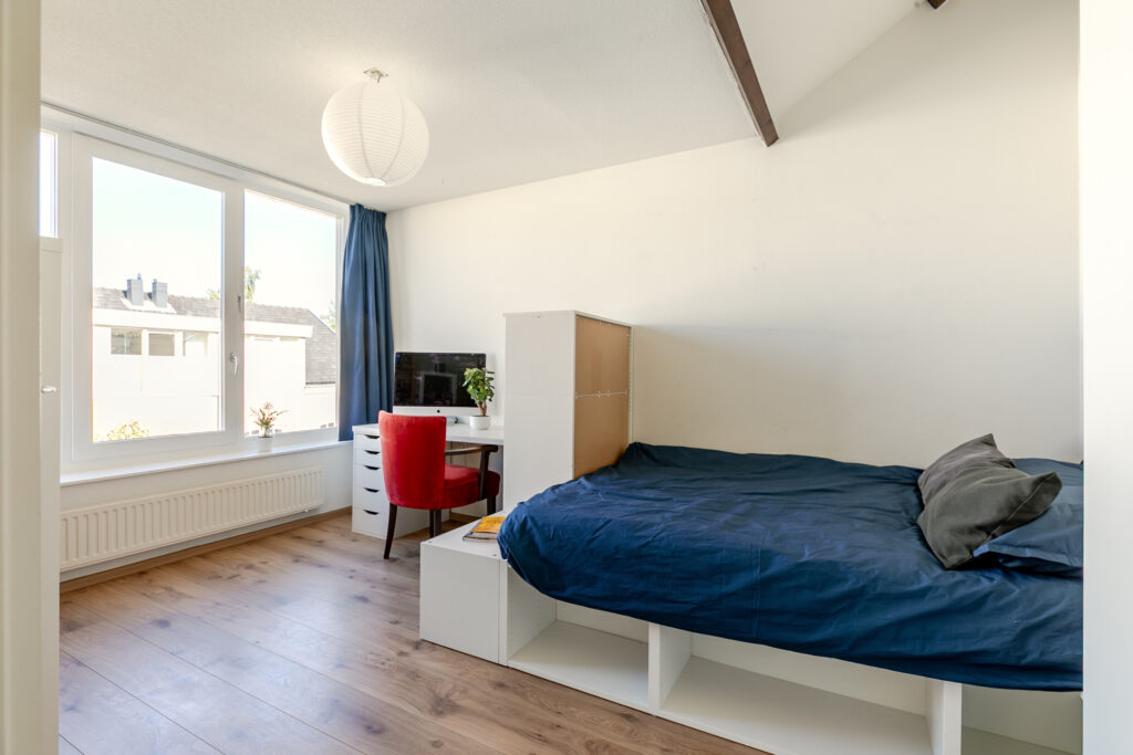 Bright bedroom with bed, desk, and large window