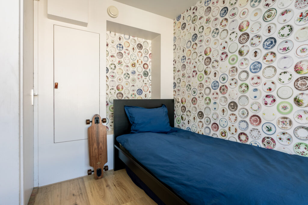 Bedroom with plate-decorated wall and skateboard.