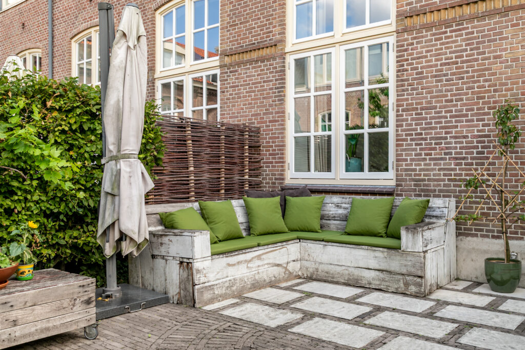 Cozy patio with cushions and brick wall backdrop.