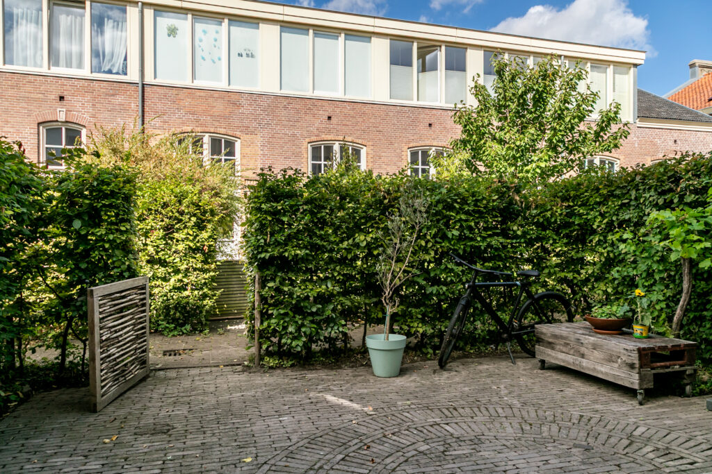 Brick building with garden, potted plants, and bicycle.