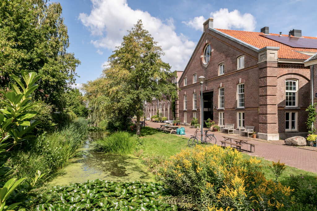 Historic brick building by a lush green canal.