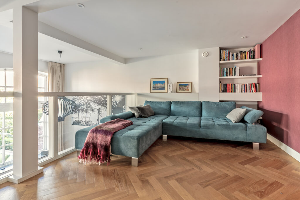 Modern living room with teal sofa and bookshelves.
