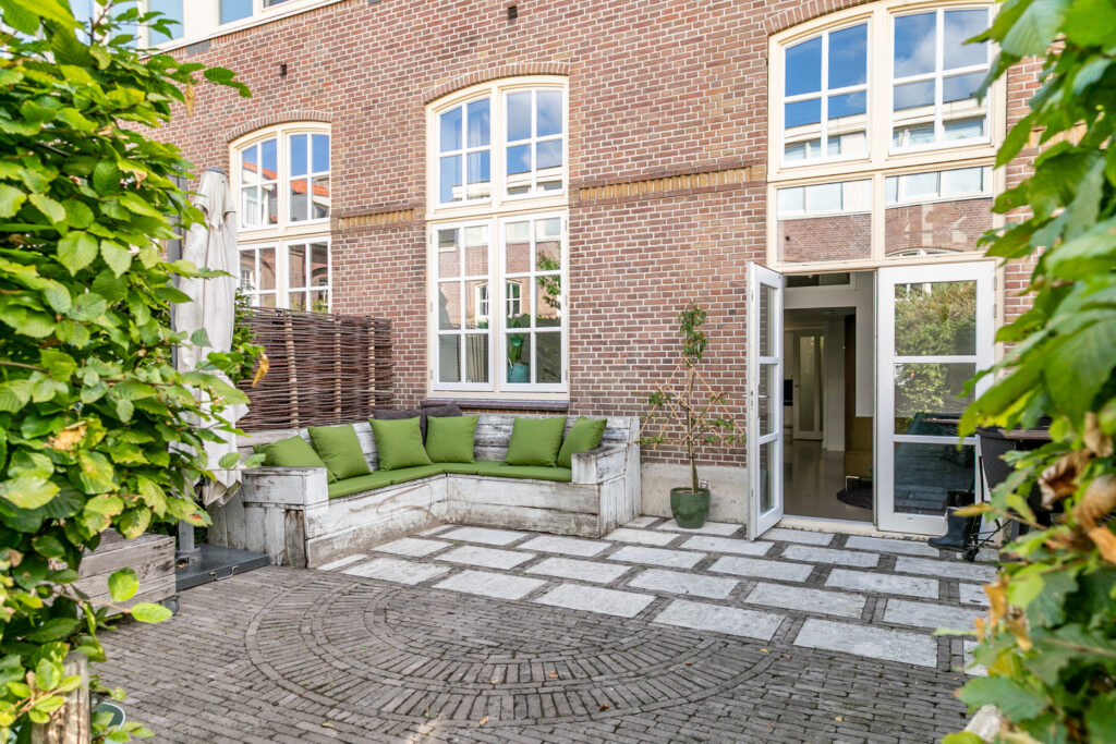 Outdoor patio with brick wall and green cushions.