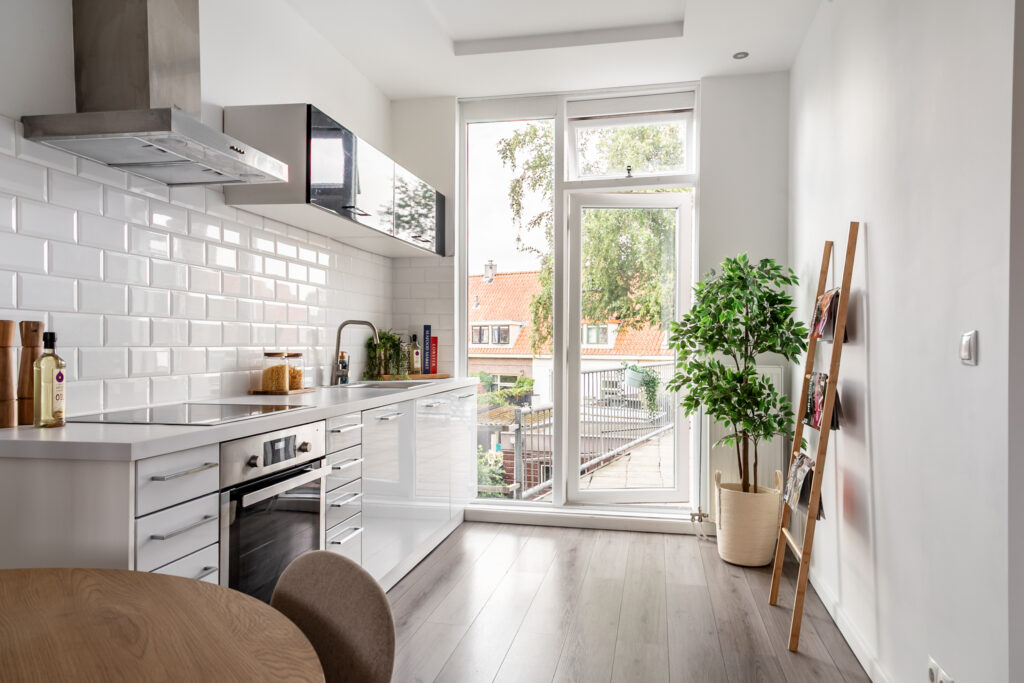 Modern kitchen with plants and large windows.