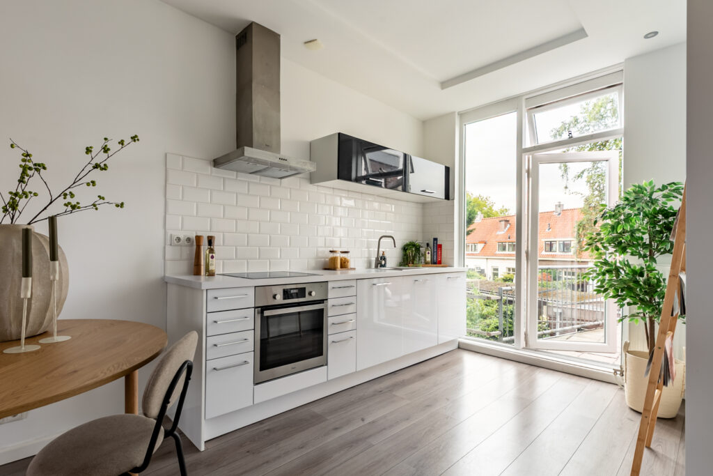 Modern kitchen with white cabinets and large window.
