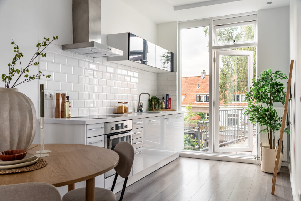 Modern kitchen with white cabinets and large windows.