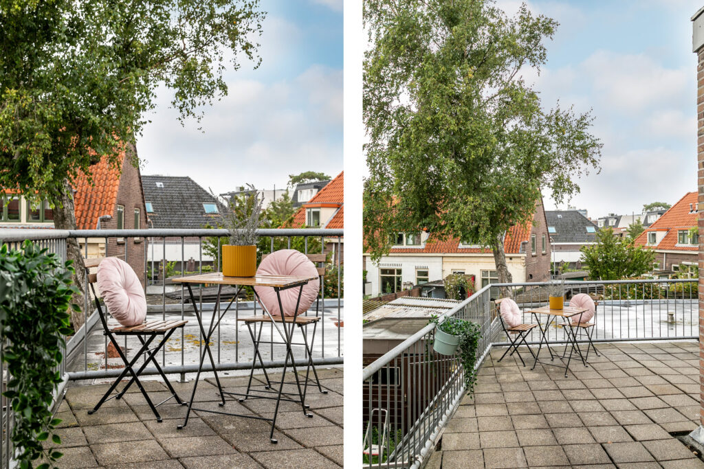 Cozy balcony with chairs and table overlooking rooftops.