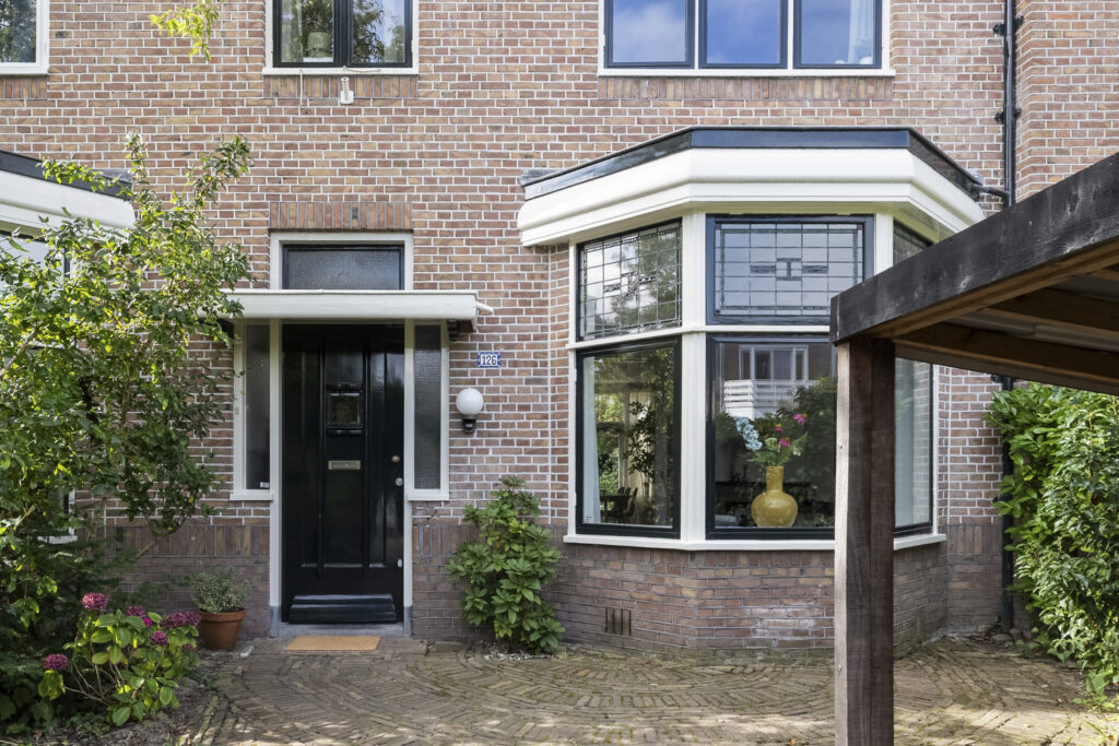 Brick house with black door and large windows.