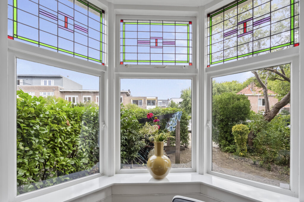 Bay window with stained glass and garden view.