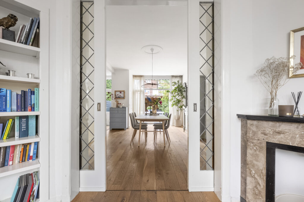 Modern dining room with wooden flooring and bookshelves.