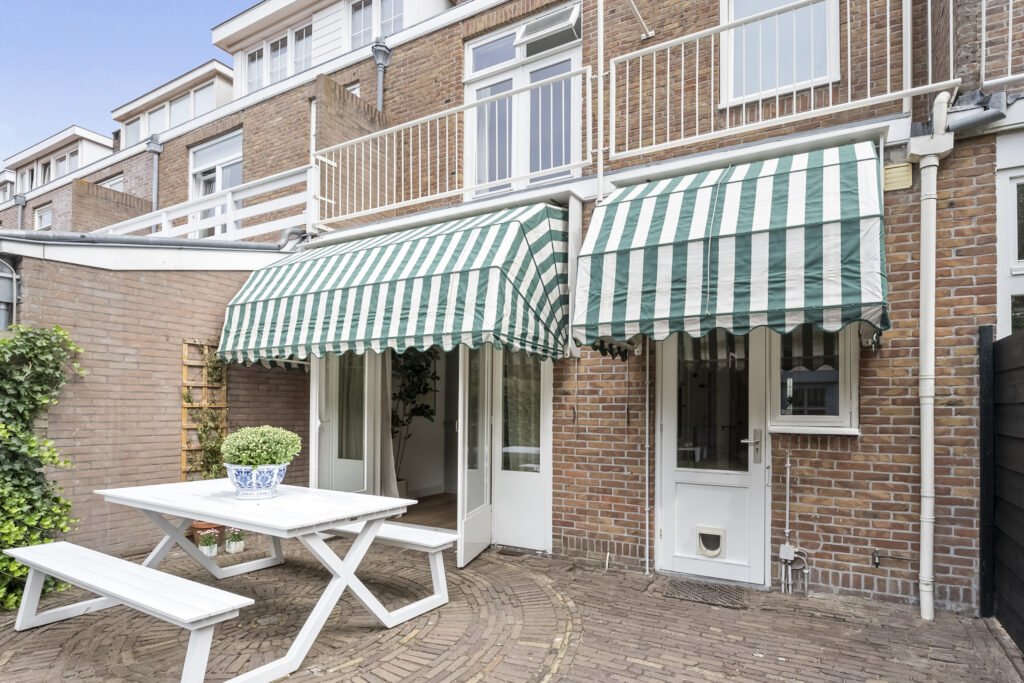 Backyard with awning and white picnic table.