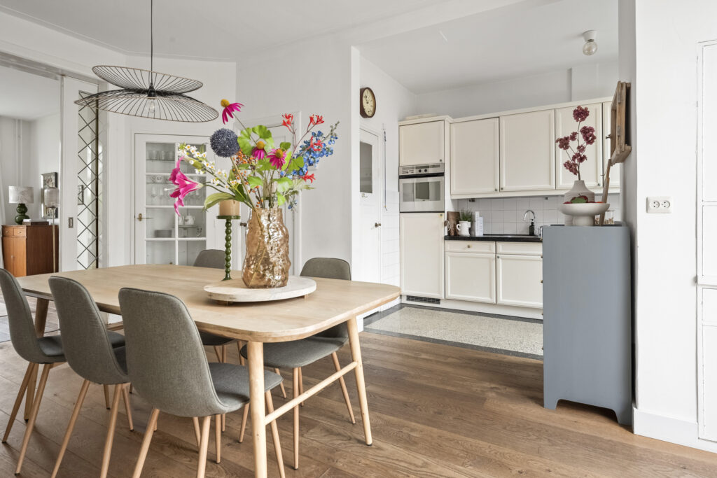 Modern kitchen with dining table and floral centerpiece.