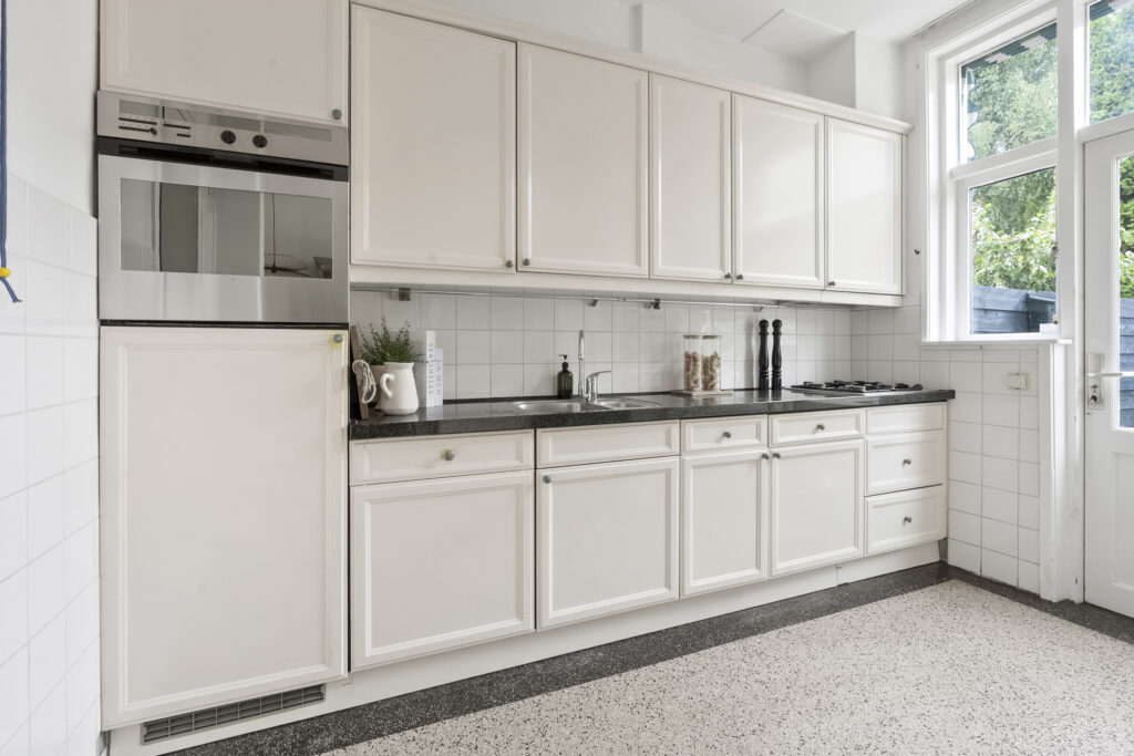 Modern white kitchen with appliances and windows.