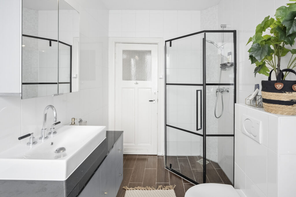 Modern white bathroom with shower and plants.