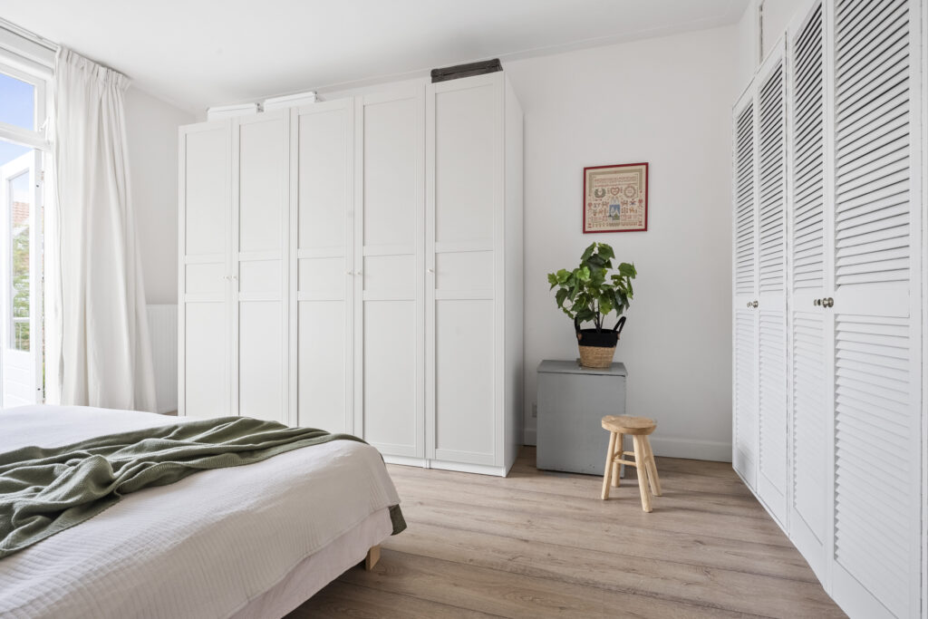 Minimalistic bedroom with white closets and wooden floor.