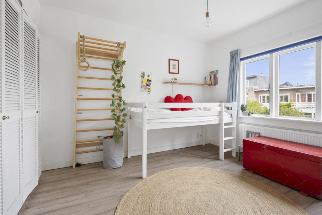 Bright children's room with bunk bed and gym ladder.