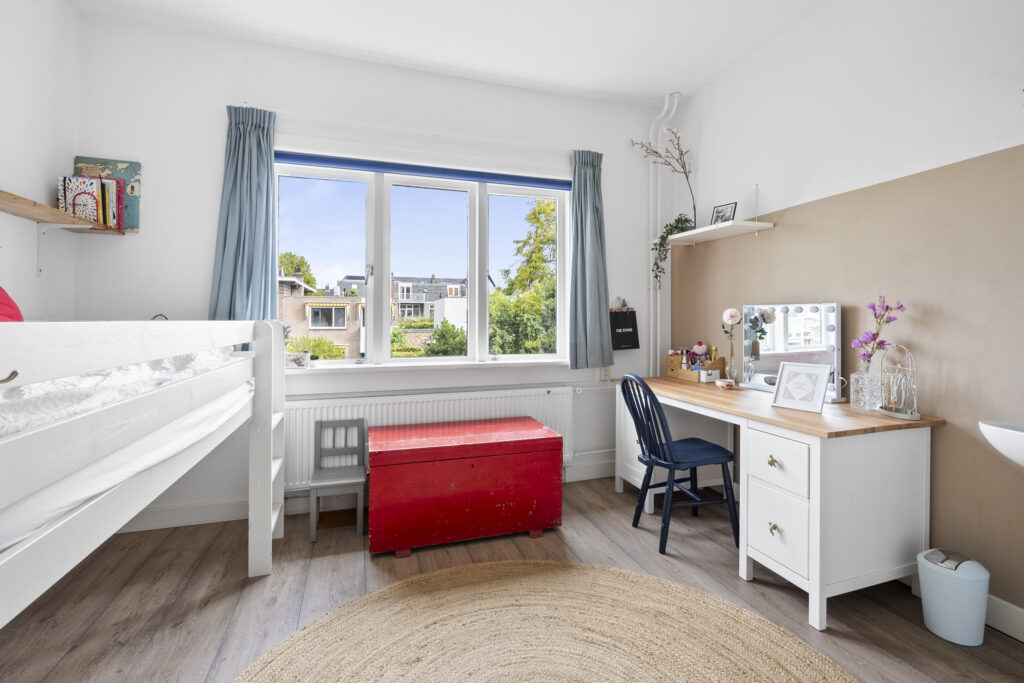 Bright bedroom with desk and large window view.