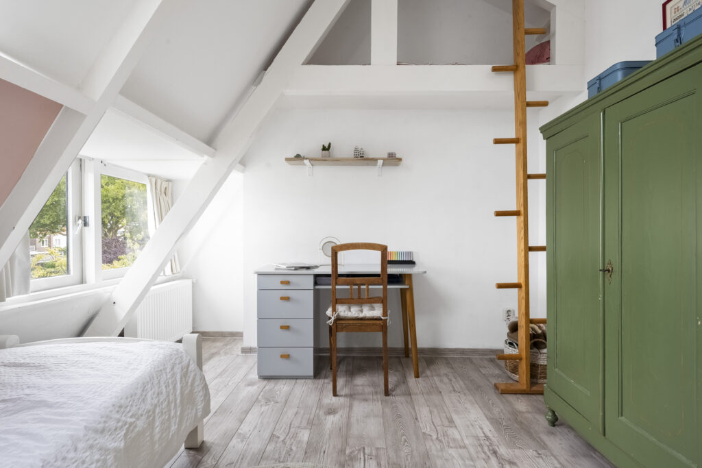 Cozy attic office with desk and wooden ladder.
