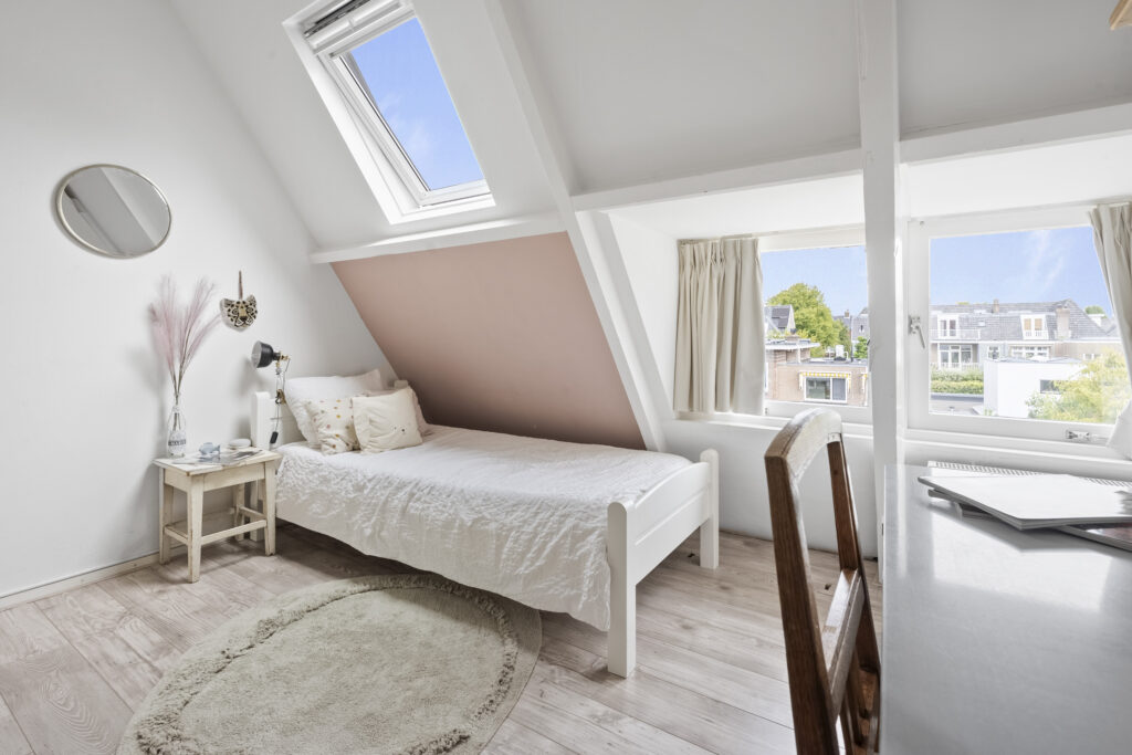 Bright attic bedroom with cozy decor and window views.