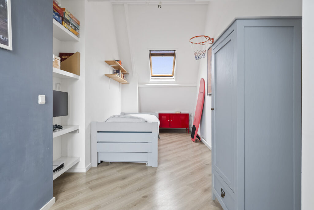 Modern bedroom with bed, surfboard, and skylight window.