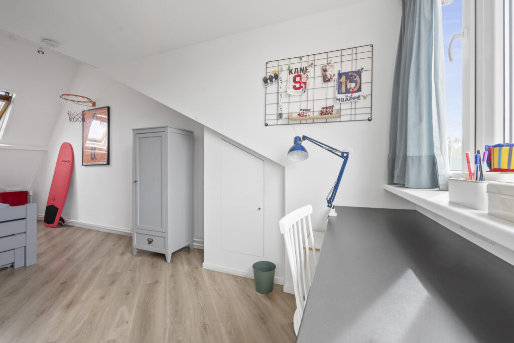 Modern attic room with desk and basketball hoop.