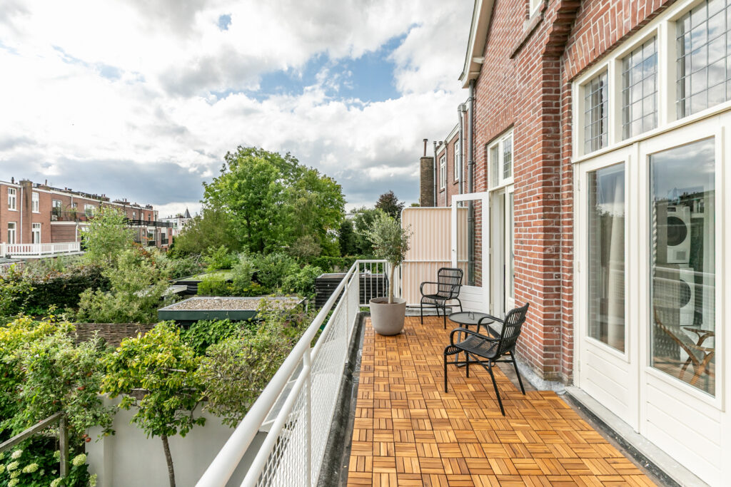 Spacious balcony with chairs overlooking lush garden.