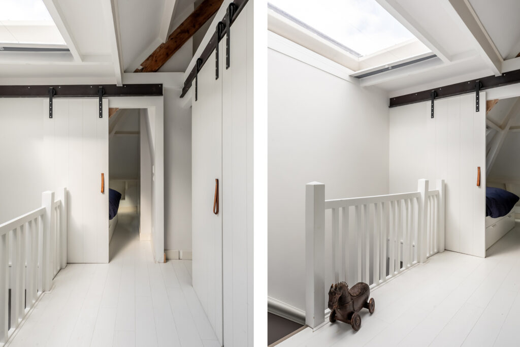 White attic with sliding barn doors and skylight.