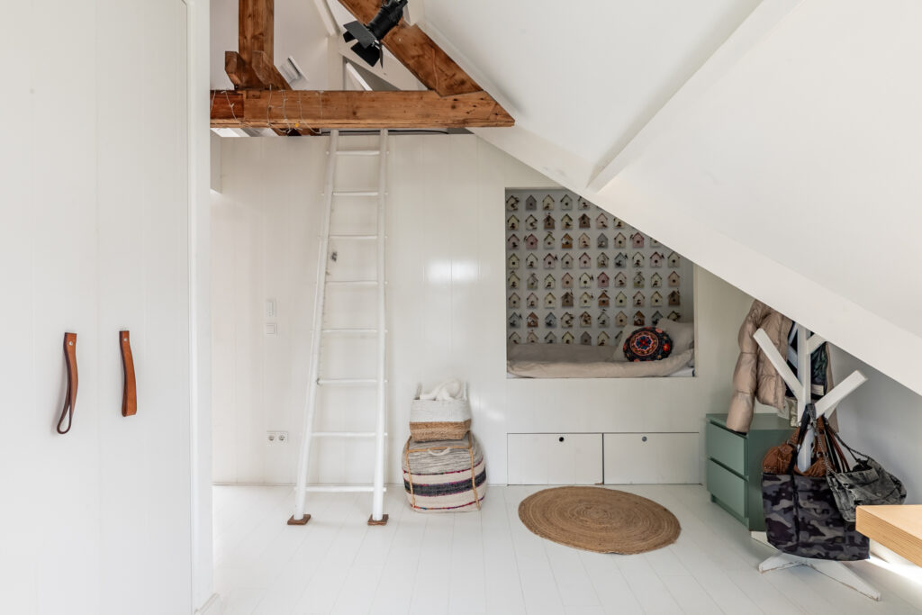 Cozy attic with ladder and seating area.