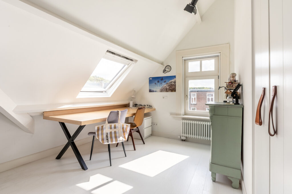 Bright attic office with desk and chairs.