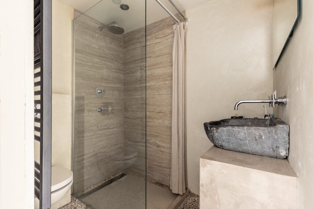 Modern bathroom with stone sink and shower.