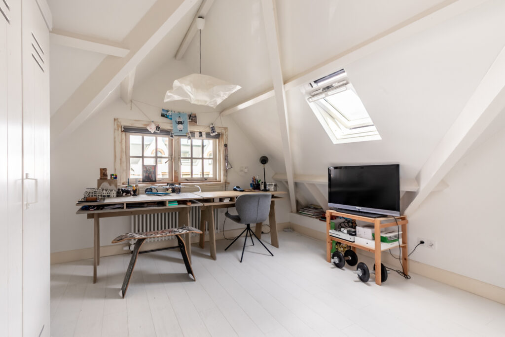 Cozy attic workspace with desk and shelves.