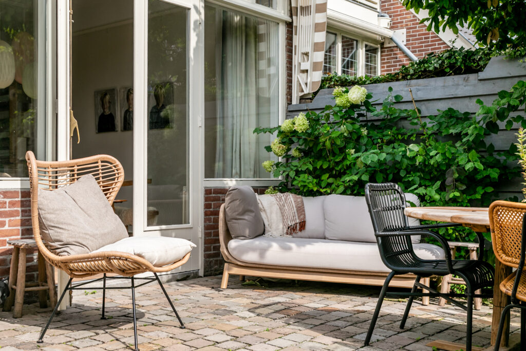 Cozy patio with wicker chairs and lush greenery.
