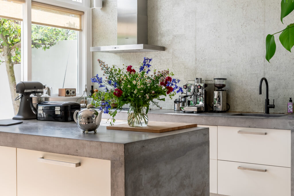 Modern kitchen with flowers and appliances on counter.