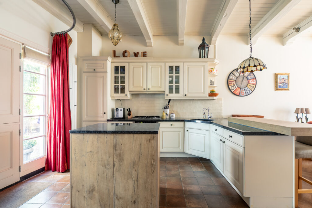 Modern kitchen with wooden cabinets and red curtains.