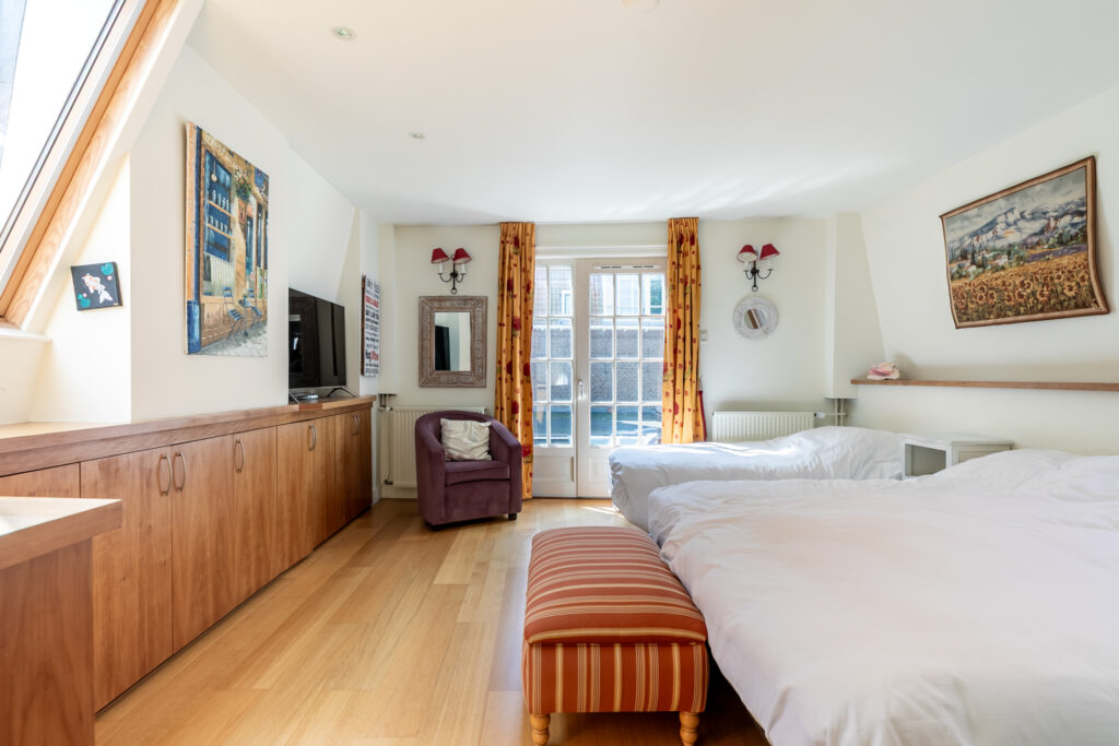Spacious bedroom with double beds and wooden floors.